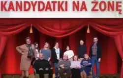 zdjęcie przedstawia część plakatu - na czerwonym tle przypominającym teatralną kurtynę, dużymi, żółtymi literami wypisany jest tytuł spektaklu: KANDYDATKI NA ŻONĘ. Nad tytułem, mniejszą czcionką i kolorem białym, widnieje napis: SPEKTAKL KOMEDIOWY. Poniże