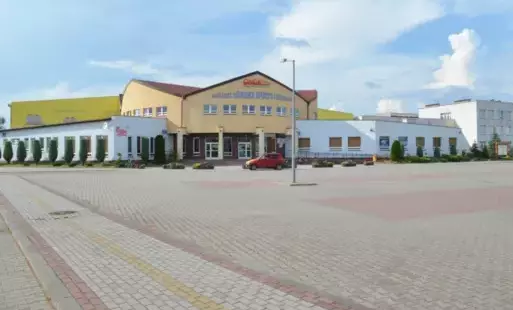 grafika poglądowa - przedstawia zdjęcie budynku parkingu i budynku MOSiR-u w Nowej Sarzynie