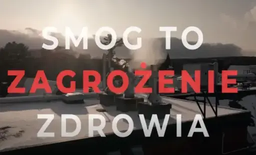 Grafika przedstawia zimowy krajobraz miejski widziany z góry — widać dachy budynków pokryte śniegiem oraz unoszący się z kominów dym. W tle znajduje się zachmurzone niebo z nisko zawieszonym słońcem, co tworzy lekko przytłumioną, zimową atmosferę.  Na śro