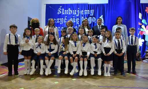 zdjęcie pierwszoklasistów pasowanych na ucznia z dyrektorem biura burmistrza jerzym paulem i dyrekcją szkoły oraz wychowawcą klasy